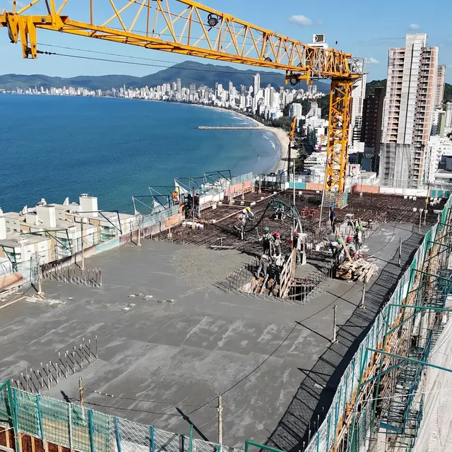 Grua sobre a última laje de uma torre, com a baía de Balneário Camboriú ao fundo