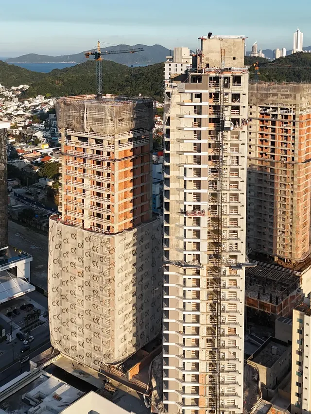 Vista aérea das duas torres do Artefacto Towers em obra, com a serra ao fundo