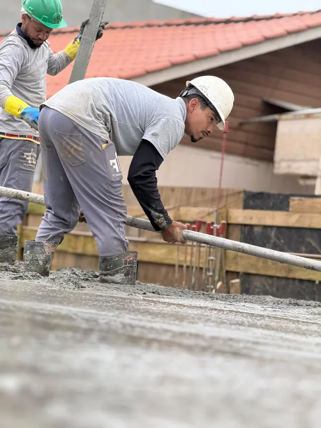 Profissional nivelando o concreto fresco com a régua